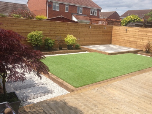 Artificial grass with raised patio area with effective sleeper edge!