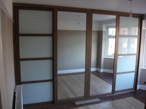 Walnut framed sliding doors with mirror and white glass.