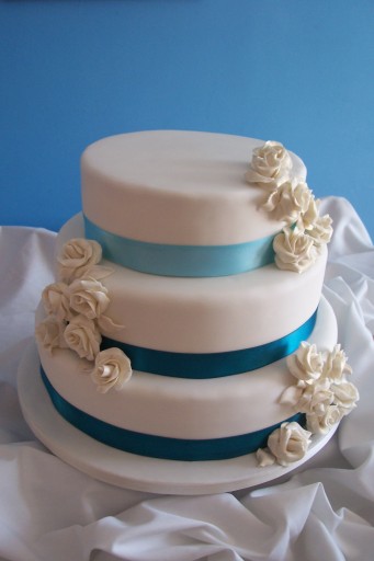 3 tier ivory wedding cake with teal ribbons and ivory sugar roses