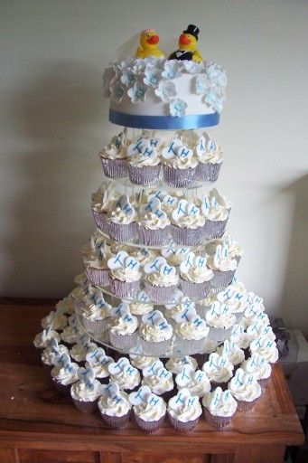 Blue and white blossom flowers tumble down a cupcake tower decorated with personalised initial ed he