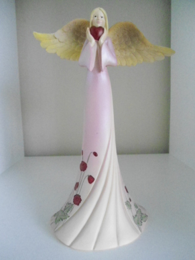 A large pink angel holding a heart in hands