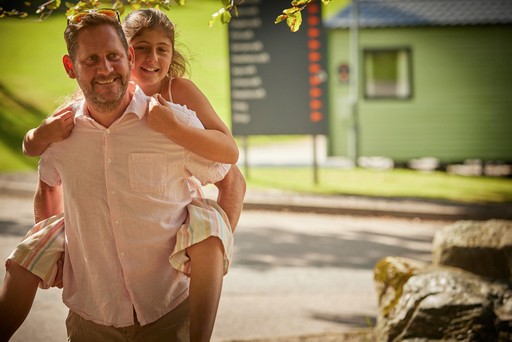 Father carrying daughter as they stroll the grounds of Hunters Quay Holiday Village
