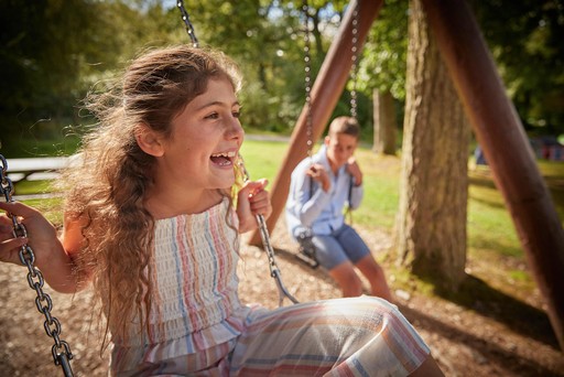 Children play on the swings of the outdoor play area at Hunters Quay Holiday Village