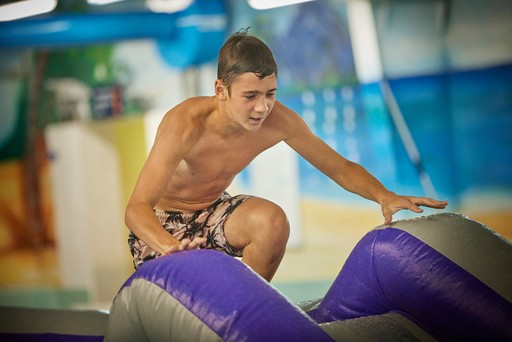 Kid climbs over an obstacle of the Go Aqua Run at Hunters Quay Holiday Village