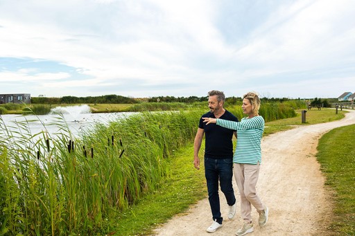 Couple walk past the Fishing Lake at Gwel an Mor