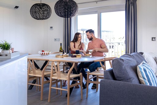 Couple sit at the dining table for lunch in one of our lodges at Gwel an Mor