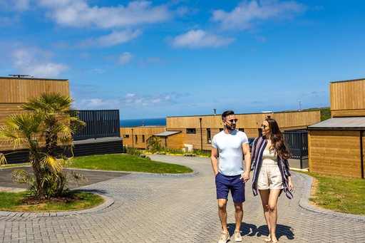 Couple walk past a selection of lodges while strolling the grounds of Gwel an Mor