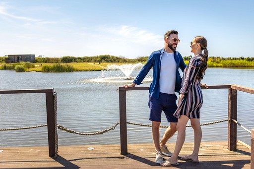 Couple stand on decking next to the Fishing Lake at Gwel an Mor