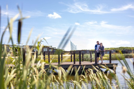Couple stand on decking next to the Fishing Lake at Gwel an Mor