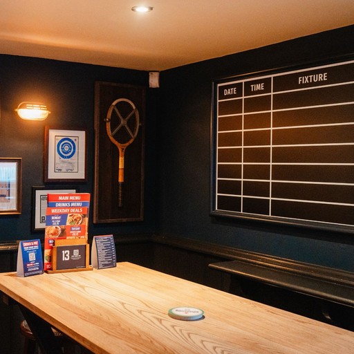 A quieter corner with table seating and a fixture board, ideal for planning match days or relaxed catch-ups.