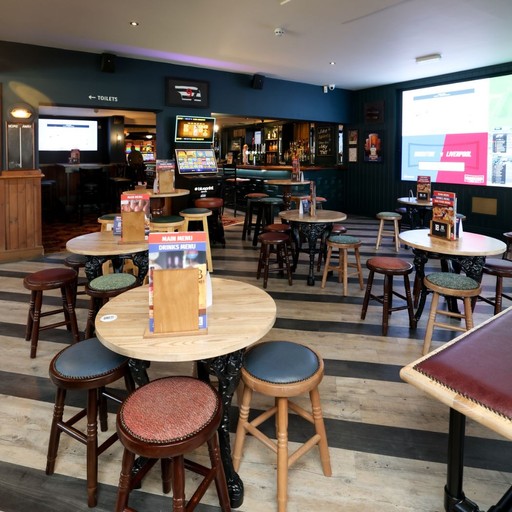 Open-plan bar area with tables, stools and large screens, perfect for drinks, dining and watching live sport.