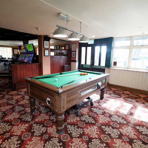 Bright pool table area with overhead lighting and natural light from nearby windows, ideal for casual games.