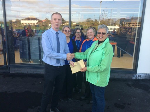 Representatives Teresa and Donna from the Wadebridge Food Bank charity accept £250 worth of B&M vouchers from store manager Jake Smith.