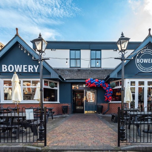 Welcoming exterior view of The Bowery with branded signage and outdoor seating, creating a friendly first impression.