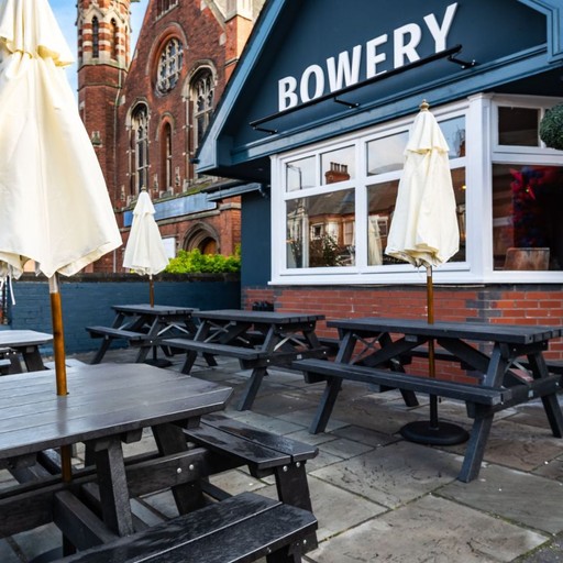 Outdoor seating area with picnic benches and parasols, ideal for enjoying drinks outside in warmer weather.