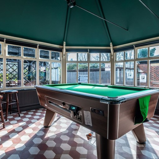Bright pool table area surrounded by large windows, offering a relaxed space for casual games and socialising.