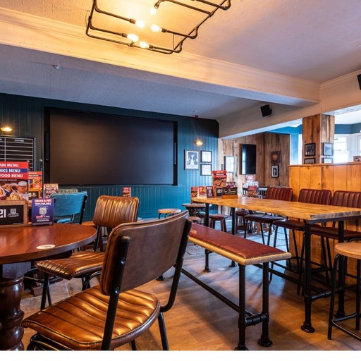 Comfortable seating area with tables and a large screen, ideal for dining, drinks and watching live sport.