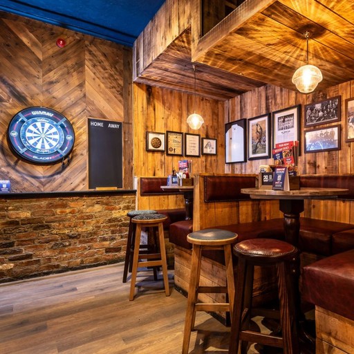 Cosy corner with a darts board, high tables and booth seating, ideal for social games and group gatherings.