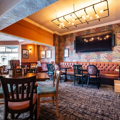 Contemporary dining space with patterned walls, booth seating and large screens, perfect for casual dining and group visits.