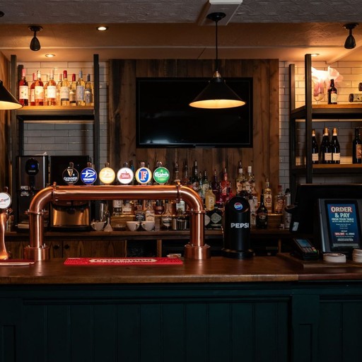 Well-stocked bar area featuring a wide selection of drinks, with stylish shelving and a central serving counter.