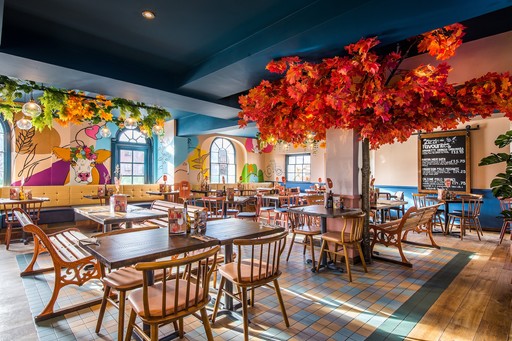 Zizzi Hereford, vibrant dining with hanging ceiling foliage and warm lighting.