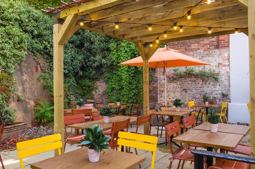 Zizzi Exeter, sheltered, charming outdoor dining space with greenery and wooden pergolas providing shade.