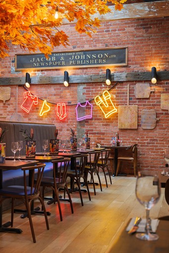 Warm Zizzi Winchester interior with vibrant décor and neon signs on wall.