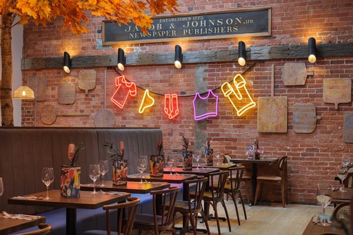 Warm Zizzi Winchester interior with vibrant décor and neon signs on wall.