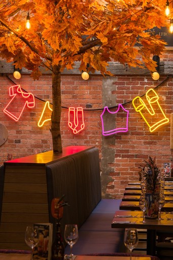 Warm Zizzi Winchester interior with vibrant décor and neon signs on wall.