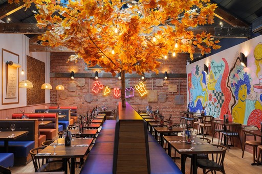 Warm Zizzi Winchester interior with vibrant décor, art murals and neon signs on wall.