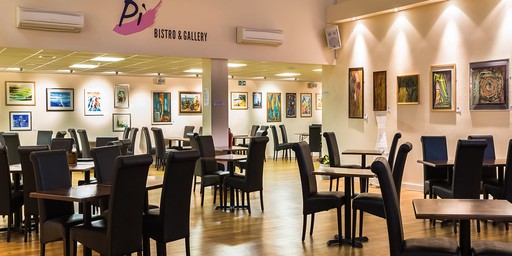 Spacious bistro with black chairs, wooden tables, and colourful art on the walls.