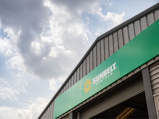 Exterior view of a Sunbelt Rentals depot showing the green signage with the yellow sunburst logo and white company name.
