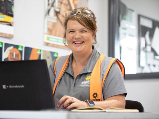 Sunbelt Rentals team member working at a depot desk with a laptop and wearing branded uniform.