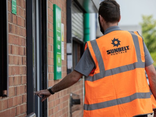 Sunbelt Rentals team member wearing a branded high-visibility vest entering a depot building.