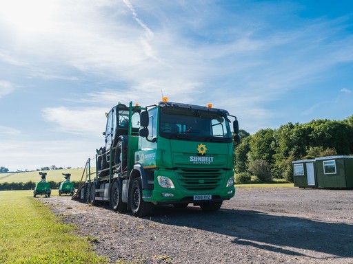 Sunbelt Rentals branded green delivery lorry transporting equipment in a rural location.