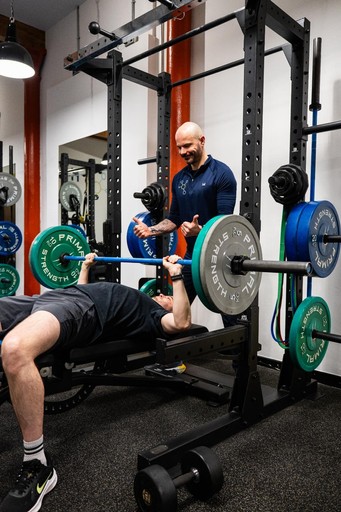 Personal trainer coaching bench press technique with a client at Health by Science Edinburgh