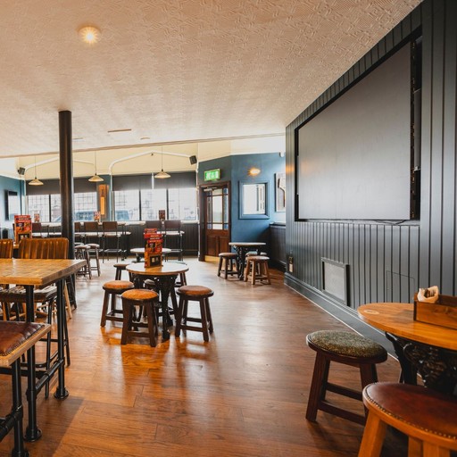 An open seating area at The Victoria Park Hotel featuring tables and a large TV screen, providing space for watching live sport with friends.