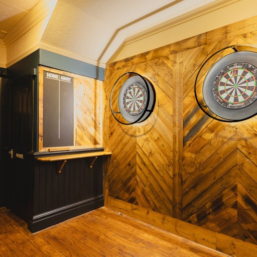 A dedicated darts area inside The Victoria Park with dartboards and a scoring board, set against a wood panelled interior for casual games.