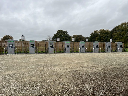An extended landscape of the InstaVolt charging setup at Frankies Farm Shop, featuring six ultra-fast chargers ready for use, surrounded by a natural setting with trees in the background