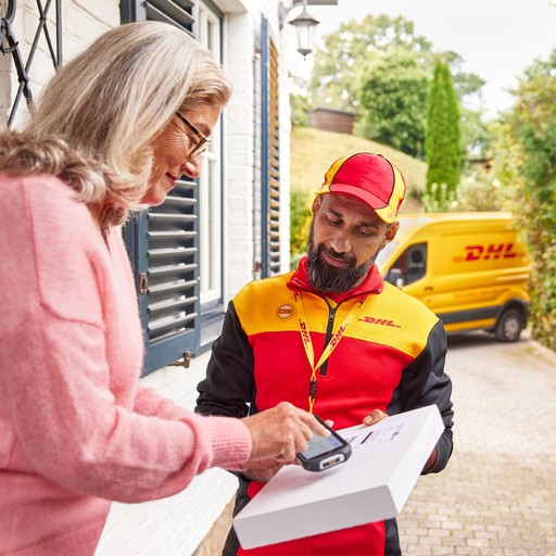 DHL Express courier assisting a customer with parcel delivery and electronic signature outside a residential property, with a yellow DHL van parked in the background.