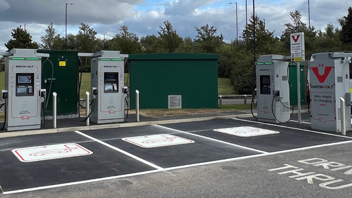 A wide shot of four InstaVolt ultra-rapid EV chargers with clearly marked bays located in the car park of McDonald’s Doncaster Road, Denaby Main. The drive-thru marking and green service unit are visible in the background.