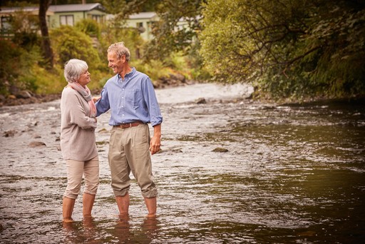 Retired couple dip their feet in the River Eachaig at Stratheck