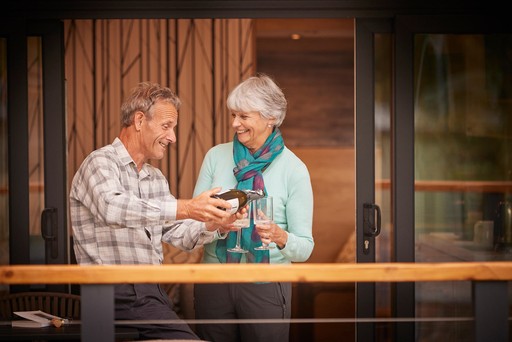 Retired couple enjoy drinks while sitting on the decking of their Forest Pod at Stratheck