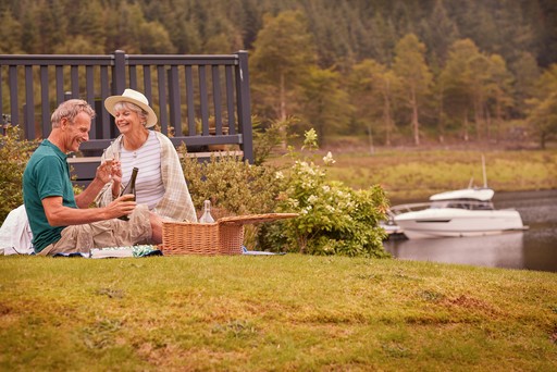 Retired couple enjoy a picnic on the banks of Loch Eck at Stratheck