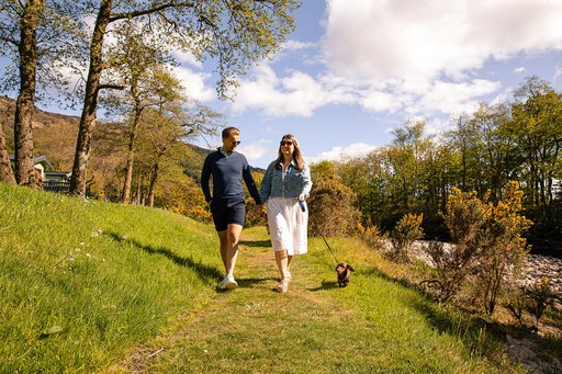 Couple take a stroll with their dog around the grounds of Stratheck Holiday Park
