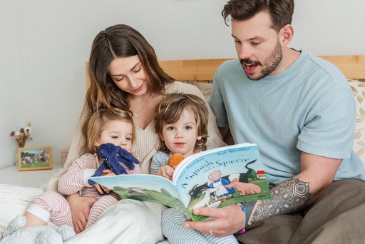 A family of four sit on the bed at home and read
