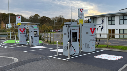 Daytime view of InstaVolt ultra-rapid EV chargers with marked bays at Ashdown Business Park in Uckfield, near a modern office building and parking spaces.