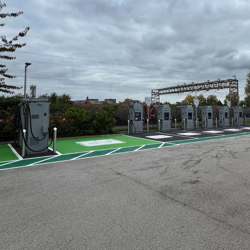 Multiple InstaVolt chargers with green-painted EV bays situated near a railway line and hedgerow in Stafford. The location provides accessible and well-marked charging spaces in a quiet retail car park setting.