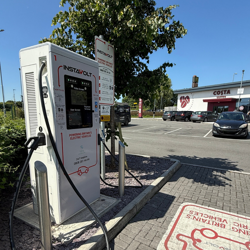 Angled view of the InstaVolt EV charger positioned at Costa Coffee in Ilminster. The Costa Coffee building and McDonald’s signage are visible in the background, alongside a marked bay for EV charging. Clear sunny weather and organised layout provide a user-friendly charging experience.