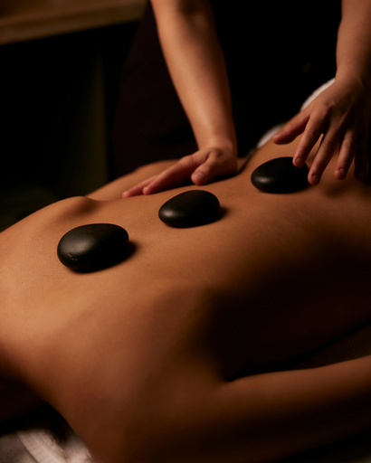 This image captures the soothing experience of a hot stone massage at the Sofitel Spa. The therapist's hands are gently placing heated stones along the client's back, while their other hand massages the shoulders. The warm, smooth stones and the therapist's skilled touch work together to relax muscles, relieve tension, and promote overall well-being.